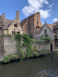 Old building by canal against sky