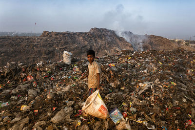 Man standing by garbage on mountain road