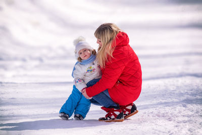 Rear view of mother with daughter against sky during winter