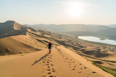 Rear view of woman walking on sand dune in badain jaran desert