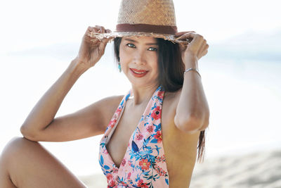 Portrait of smiling young woman wearing hat on beach