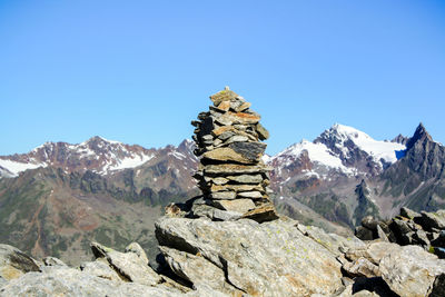 Stack of rocks on mountain against clear blue sky