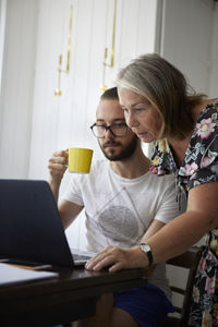 Senior woman using laptop with adult son