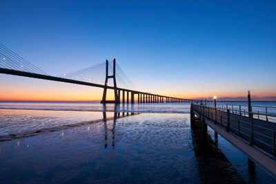 Bridge over sea against clear sky during sunset