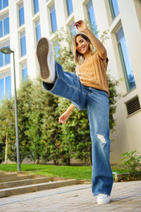 Full length of young woman exercising on footpath