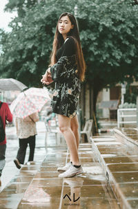 Full length of woman with umbrella in rain