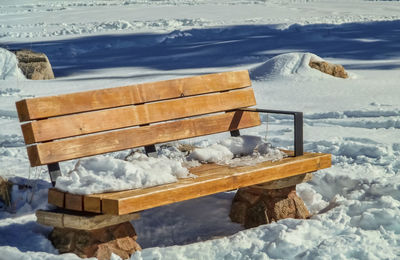 Wooden bench on snow covered field