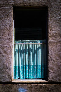 Close-up of window with blue curtain