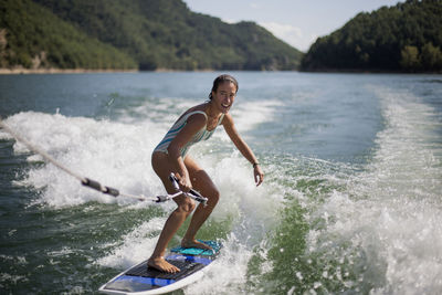 Man surfing in sea against mountains