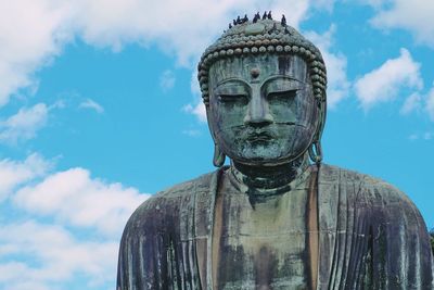 Statue of buddha against cloudy sky