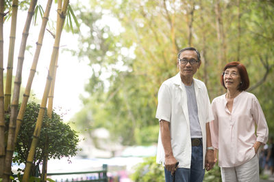 Senior couple standing by railing against trees