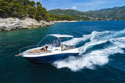 Boat sailing in sea against mountain