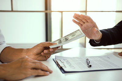 Midsection of woman holding paper with text on table