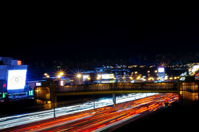 Light trails on road in city against sky at night