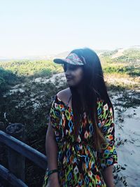 Beautiful woman standing by tree against sky