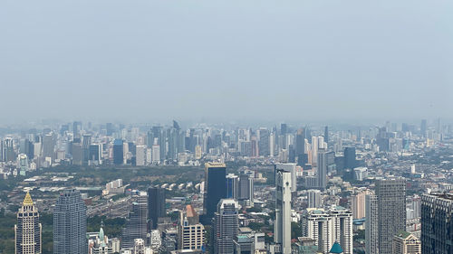 Aerial view of buildings in city against clear sky