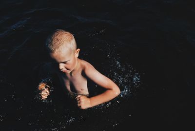 High angle view of shirtless boy swimming in lake