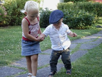 Sister holding hand of brother walking in yard