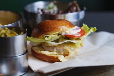 Big burger with tomato on a white plate in a restaurant