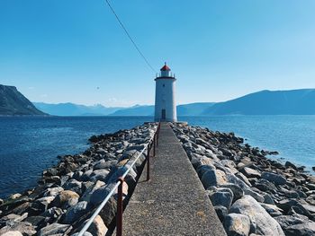 Exploring norway, mountain range and fjord, lighthouse and pier by the seaside, sunlight, blue sky