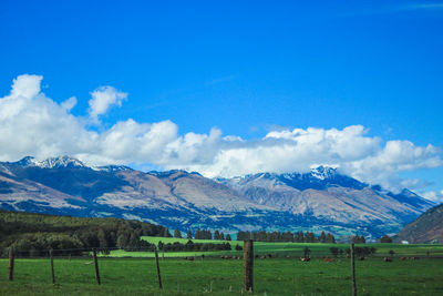 Scenic view of field and mountains against blue sky