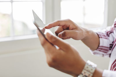 Cropped hands of businessman using tablet computer in office