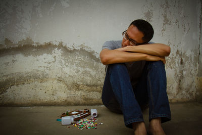 Tired man sitting against wall