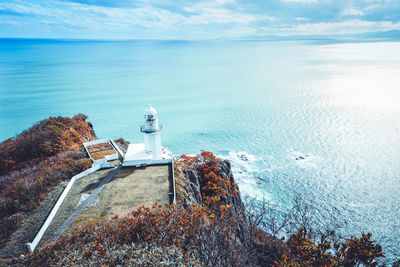 Lighthouse by sea against sky