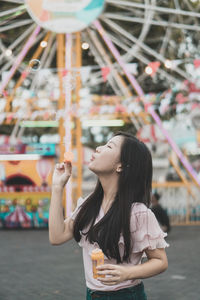 Young woman blowing bubble at amusement park