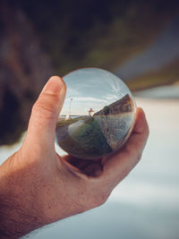 Close-up of hand holding sunglasses against sky