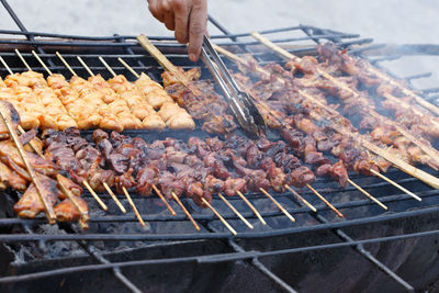 Midsection of person preparing food on barbecue grill