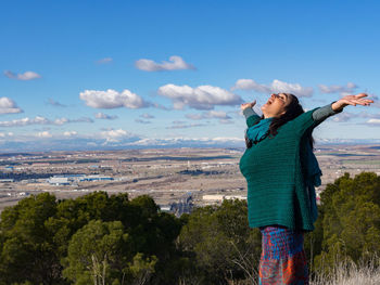 Young woman standing against sky