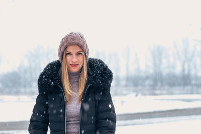 Portrait of smiling young woman standing in snow