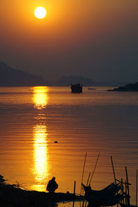 Silhouette boats in sea against sky during sunset