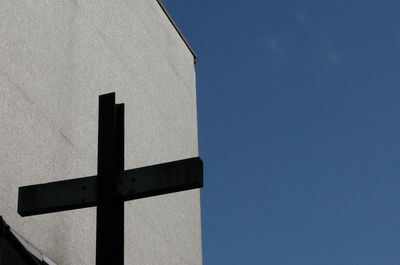 Low angle view of cross against concrete wall