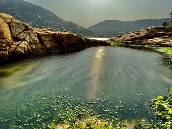 Scenic view of sea by mountains against sky