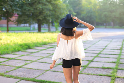 Rear view of woman standing on footpath