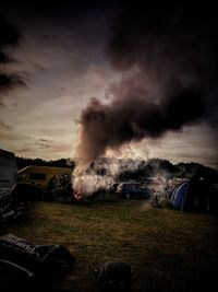 Smoke emitting from car on field against sky