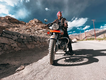 Man riding bicycle on mountain against sky