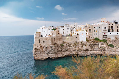 Buildings by sea against sky