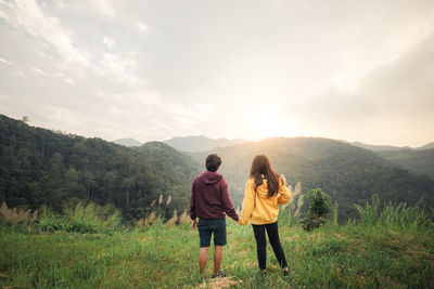 Couple making heart shape with hands and enjoy the sunset view on mountain peak