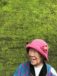 Thoughtful senior woman against mossy wall outdoors