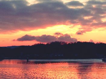 Scenic view of lake against cloudy sky at sunset