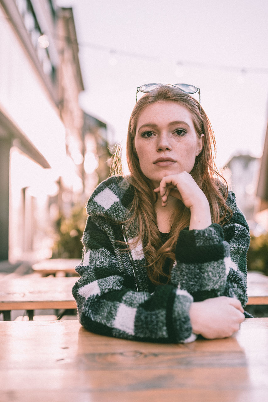 one person, young women, young adult, real people, lifestyles, portrait, sitting, hair, front view, leisure activity, long hair, women, looking, adult, table, beautiful woman, looking away, hairstyle, contemplation, warm clothing