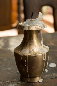 Close-up of candle in metallic container on table