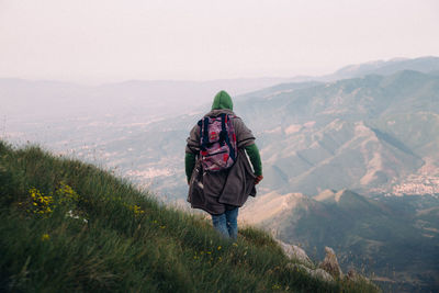 Rear view of man looking at mountains against sky
