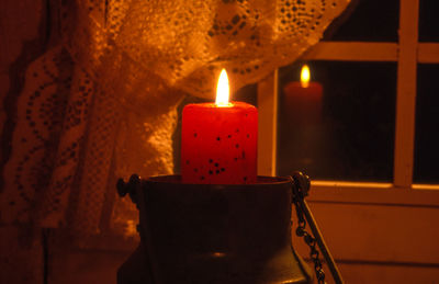 Close-up of lit candle against the window