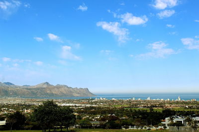 Aerial view of townscape by sea against sky