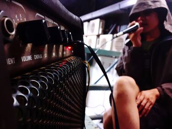 Woman holding microphone while sitting on seat