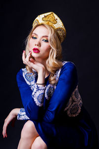 Beautiful woman sitting against black background